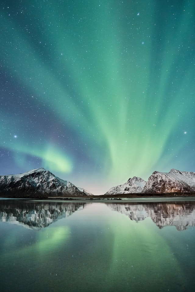 Northern lights and stars over mountains and lake